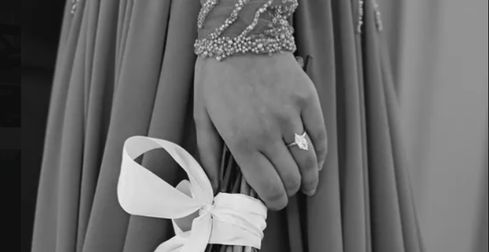 Bride's hand showing her ring, holding a ribbon-wrapped bouquet